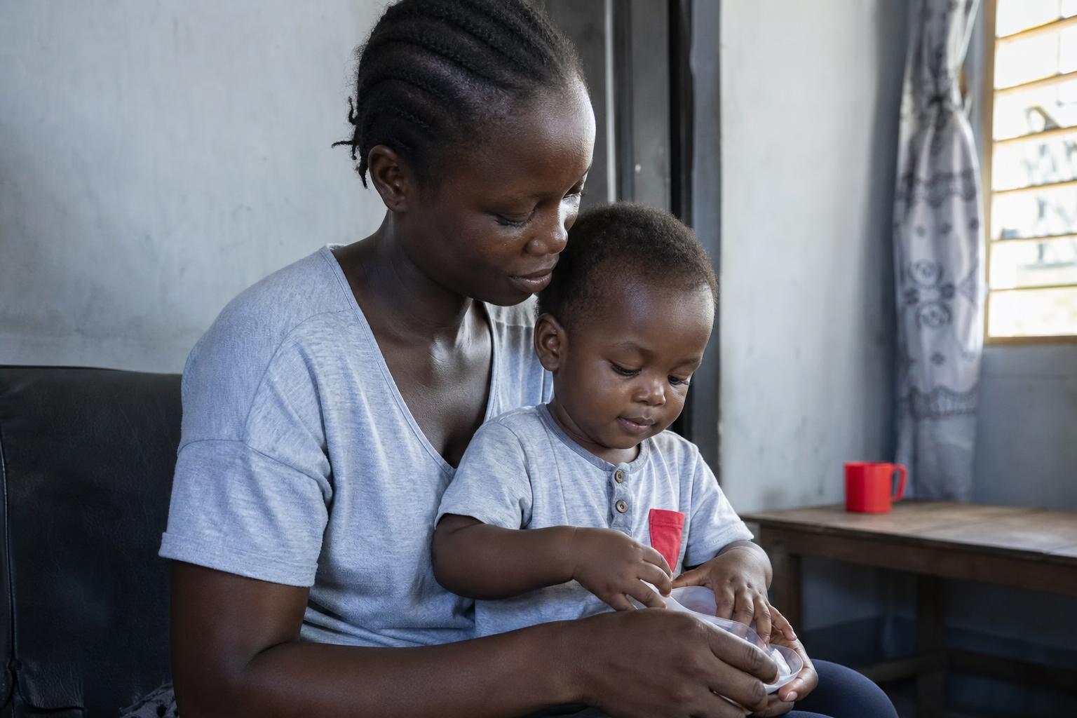 A Nigerian mother with her young child in a tender routine moment at home.