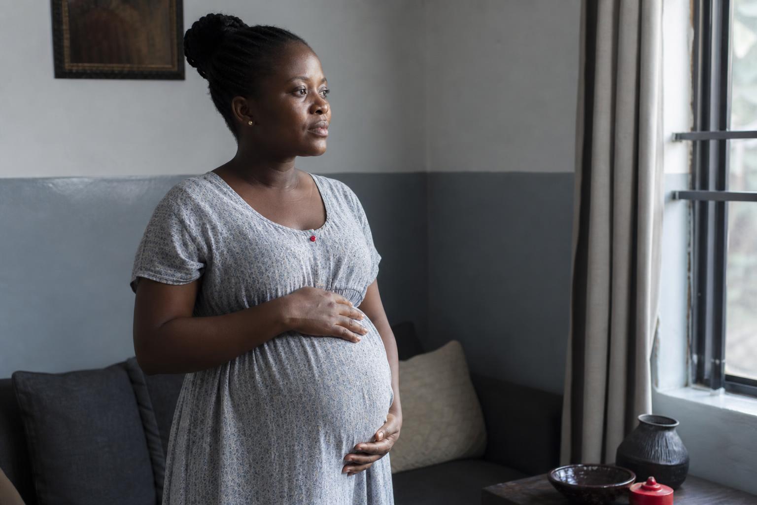 A pregnant Nigerian woman in a calm routine moment at home, mid-pregnancy.